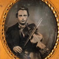 Ambrotype photograph of a young man playing the fiddle. Bound in a brown leather frame.