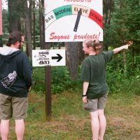 Two campers confused by direction sign.
